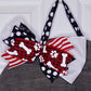 Dog bandana with a large bow featuring red, white, and black patterns on a gray surface.