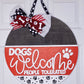 Decorative door hanger with 'Dogs Welcome, People Tolerated' text and bows on a white background