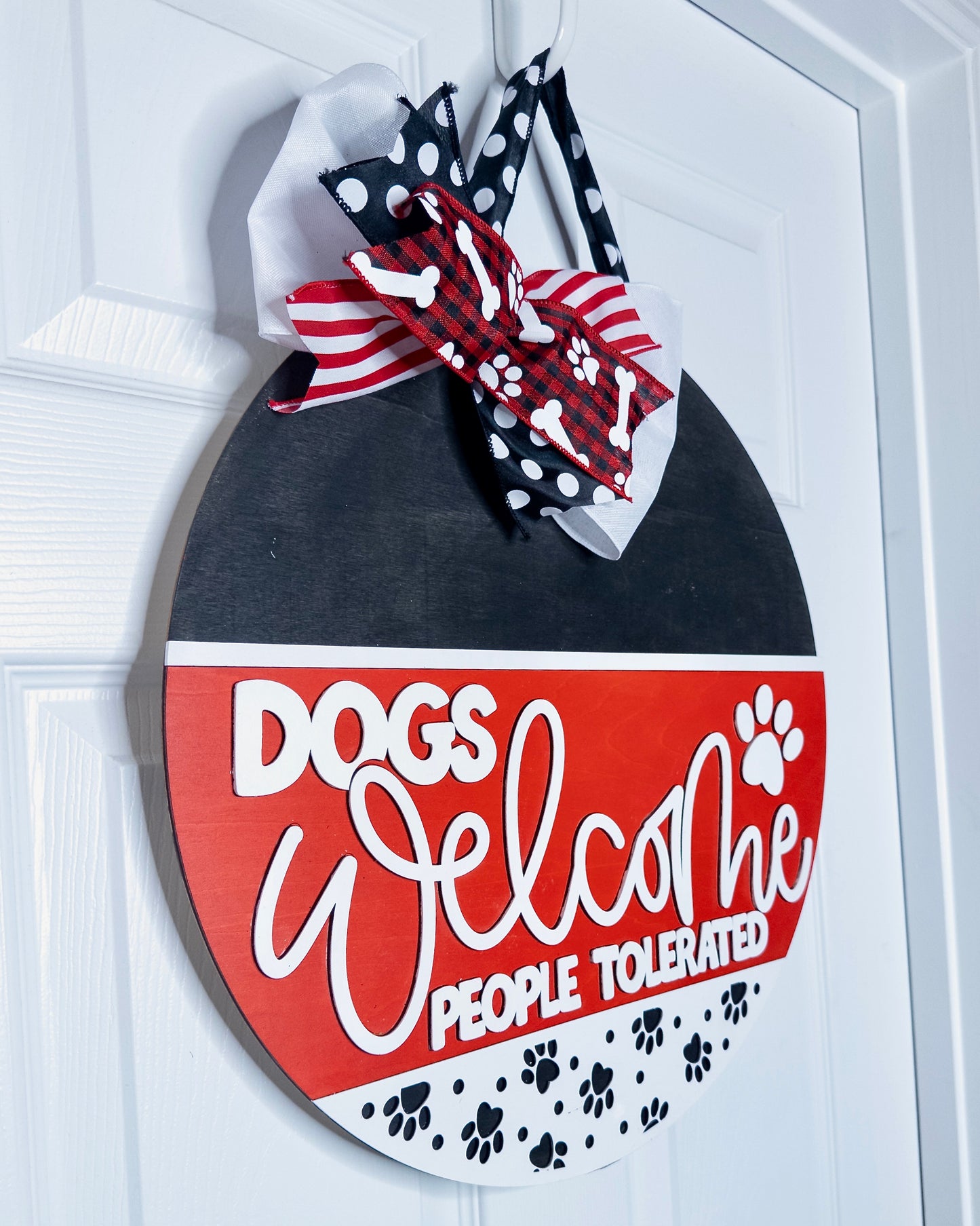 Decorative sign with 'DOGS Welcome, PEOPLE Tolerated' text on a white door.