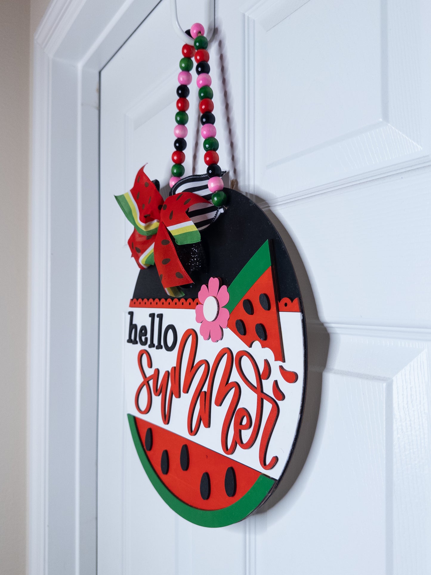 Decorative door hanger shaped like a watermelon with 'hello summer' text on a white door.