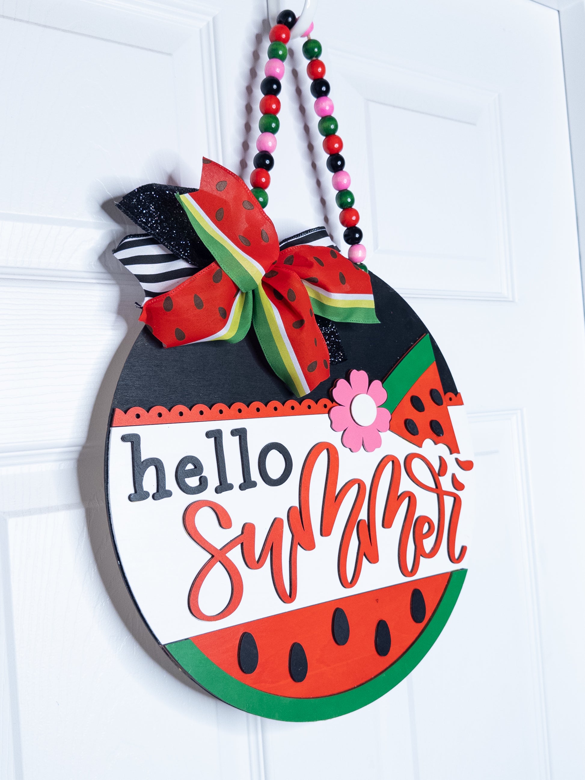 Decorative sign shaped like a watermelon with 'hello summer' text on a white background