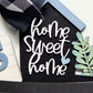 Decorative sign with 'Home Sweet Home' text on a black background, surrounded by decorative elements.
