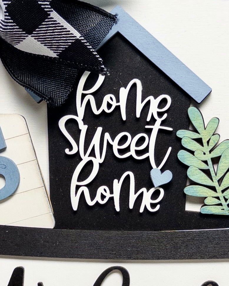 Decorative sign with 'Home Sweet Home' text on a black background, surrounded by decorative elements.