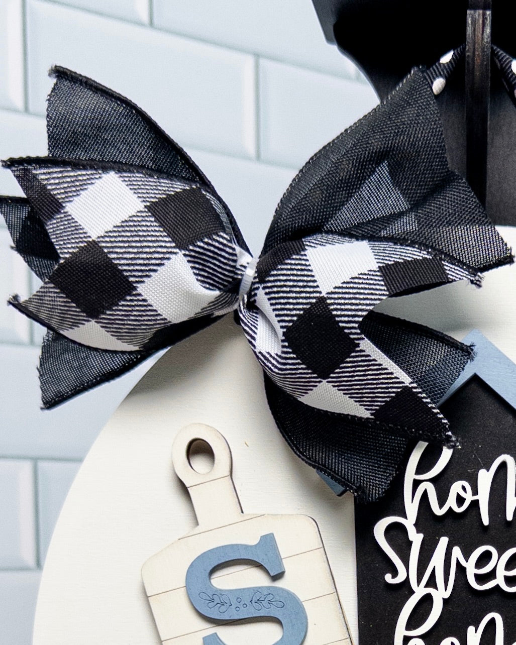 Decorative wreath with a black and white checkered bow on a white background