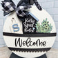 Decorative sign with 'Home Sweet Home' and 'Welcome' text, featuring a black and white checkered bow.