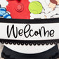 Decorative sign with cartoon characters and the word 'Welcome' on a white background