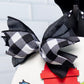 Black and white checkered bow on a toy fire hydrant with a white tiled background