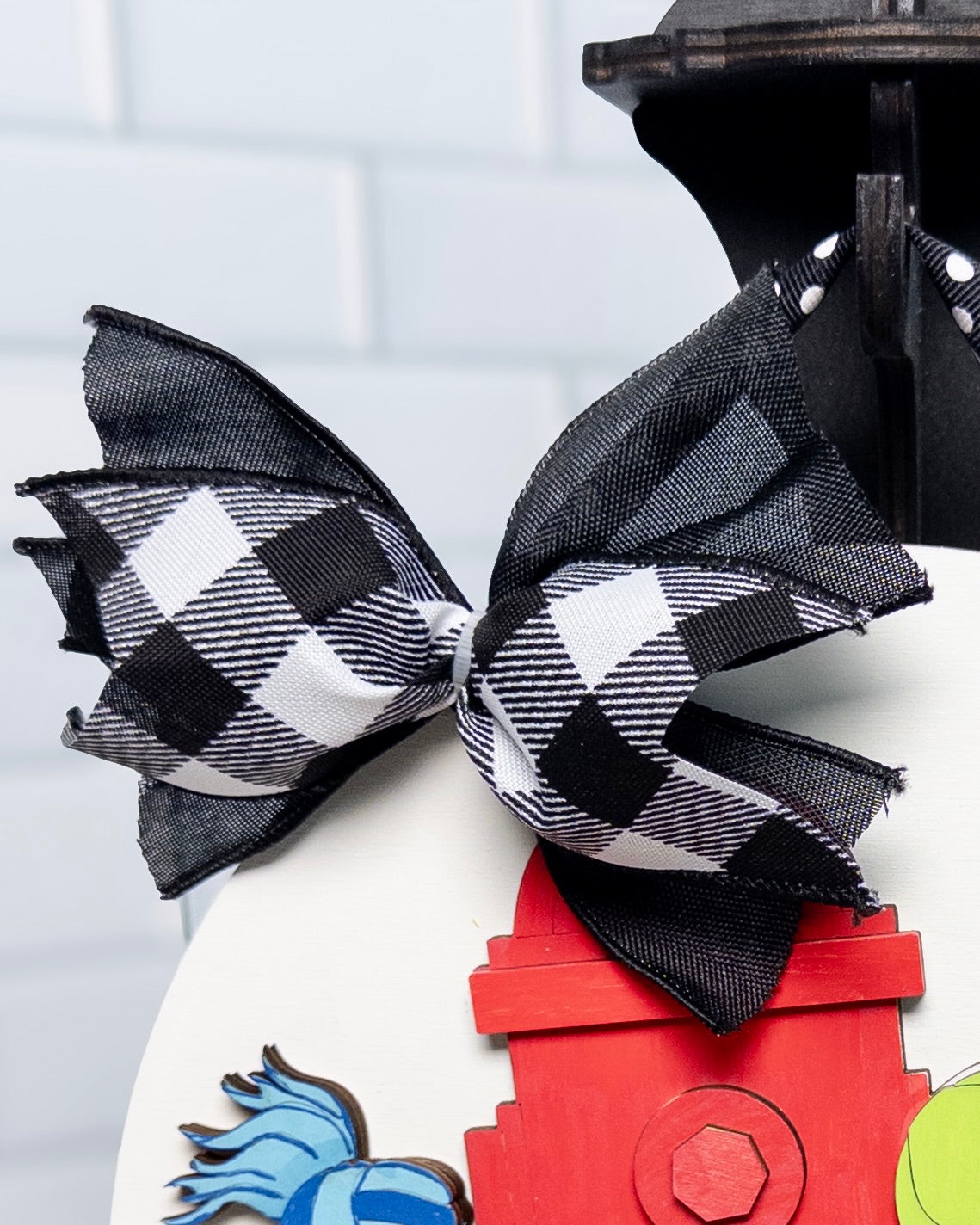 Black and white checkered bow on a toy fire hydrant with a white tiled background