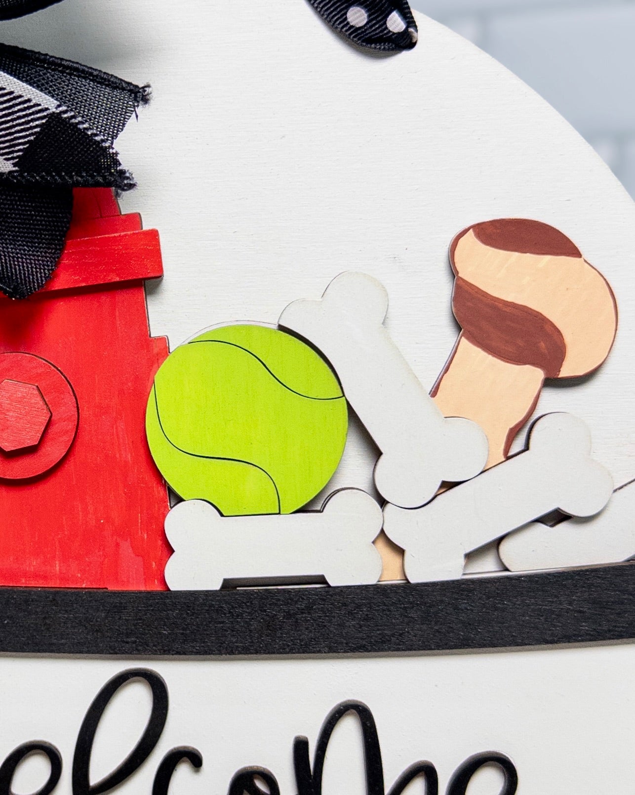 Decorative sign with dog-themed cutouts including a bone, ball, and house on a white background.