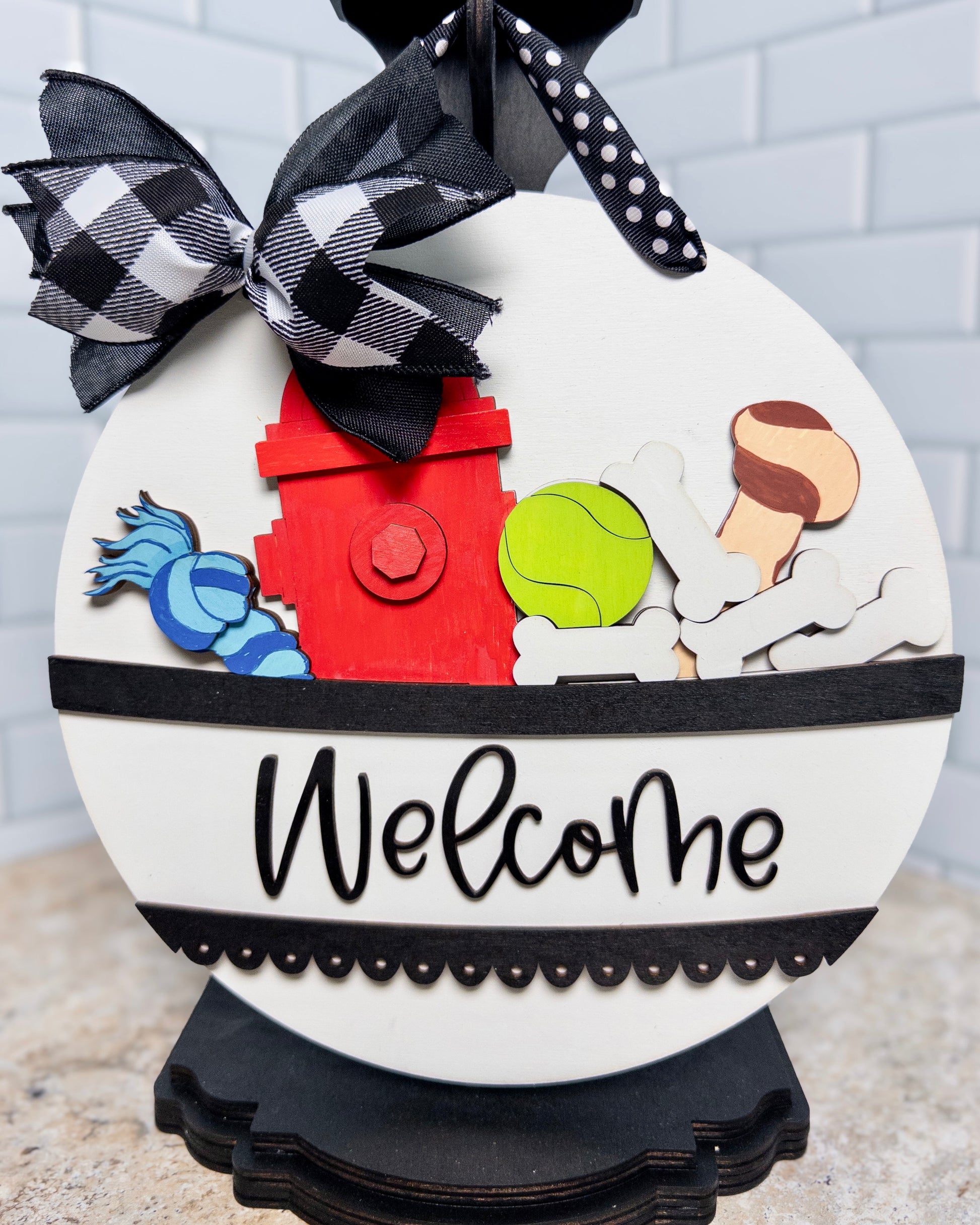 Decorative sign with cartoon characters and 'Welcome' text, featuring a black and white checkered bow.