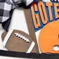 Decorative items including a football, checkered ribbon, and letter 'G' on a white background