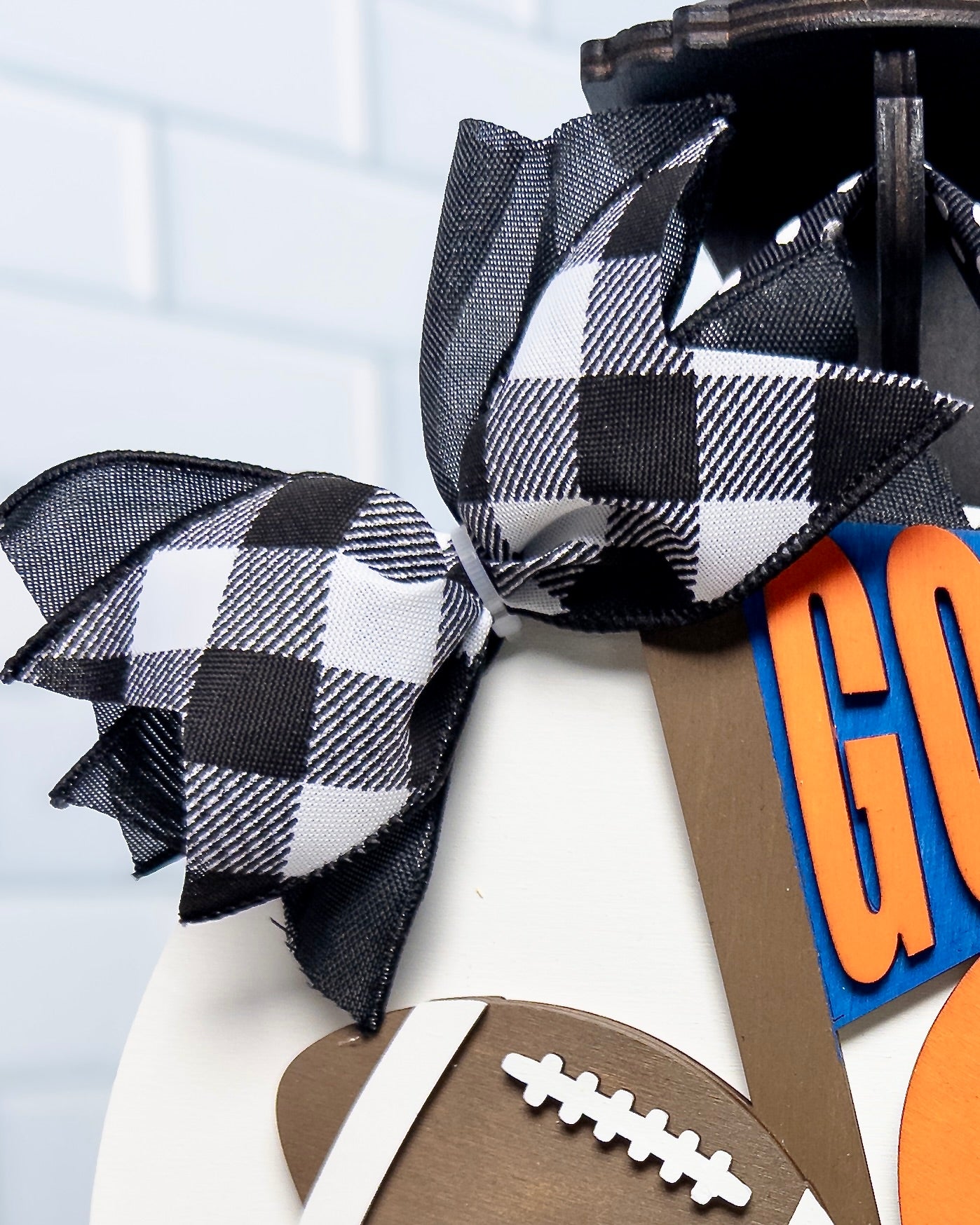 Black and white checkered bow with football and 'GO' sign on a light blue background