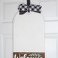 Decorative door hanger with 'Welcome' sign and plaid ribbon on a white door.