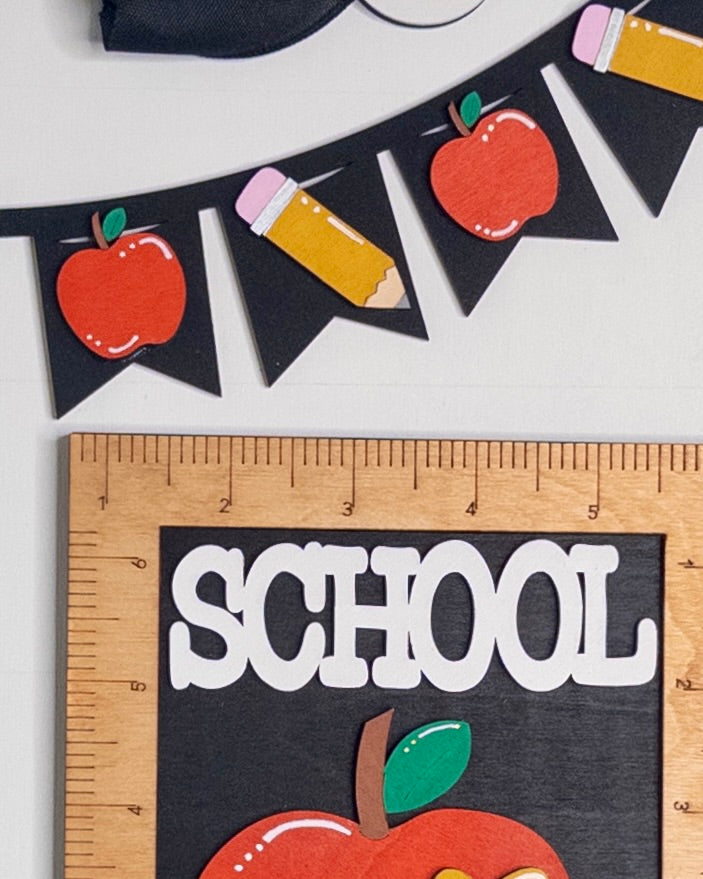 Decorative banner with apples and pencils next to a ruler with 'SCHOOL' text on a white background