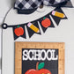 Decorative school-themed item with apple, pencil, and banner design on a white background.