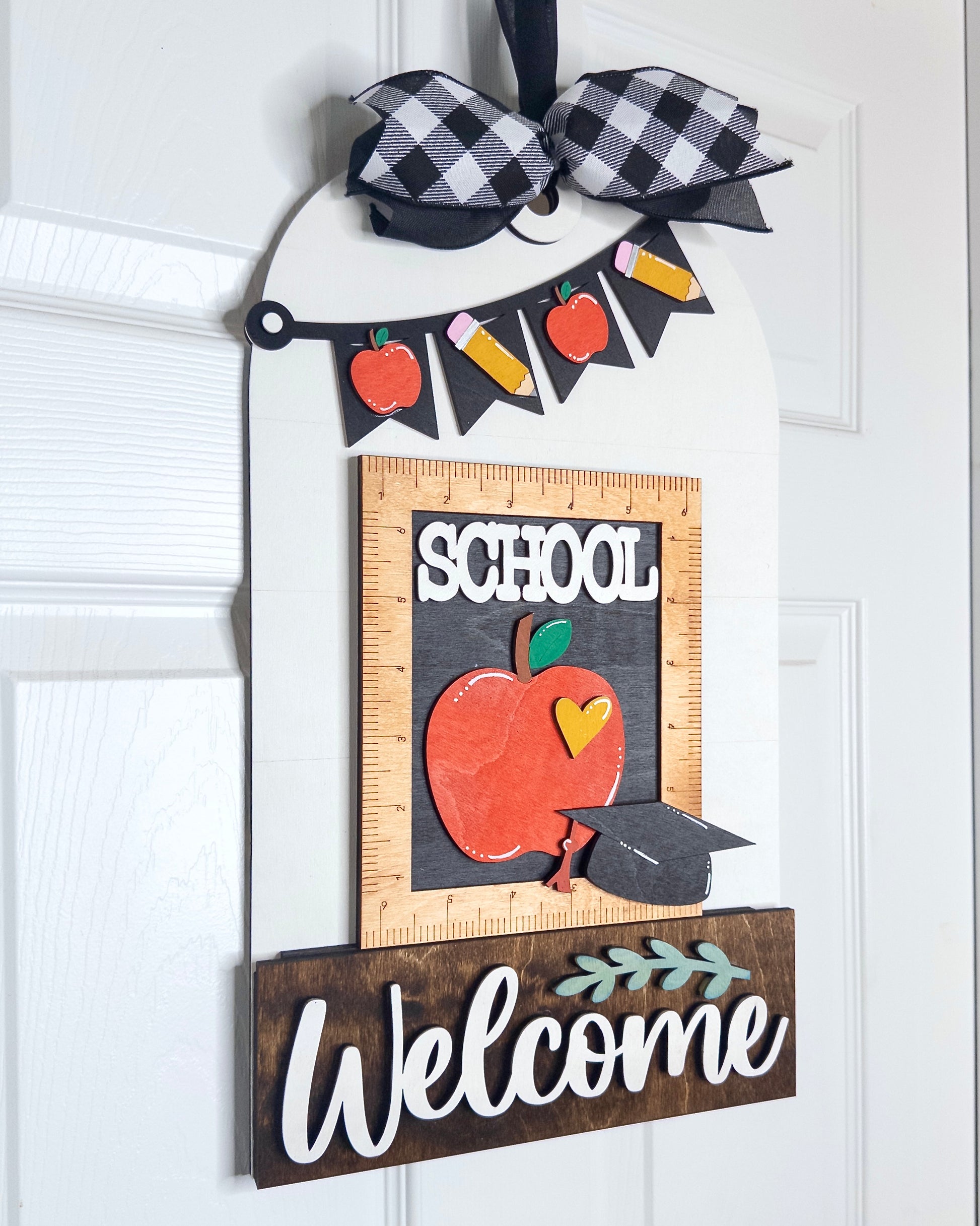 Decorative door hanger with 'School Welcome' text, apple illustration, and banner on a white background.