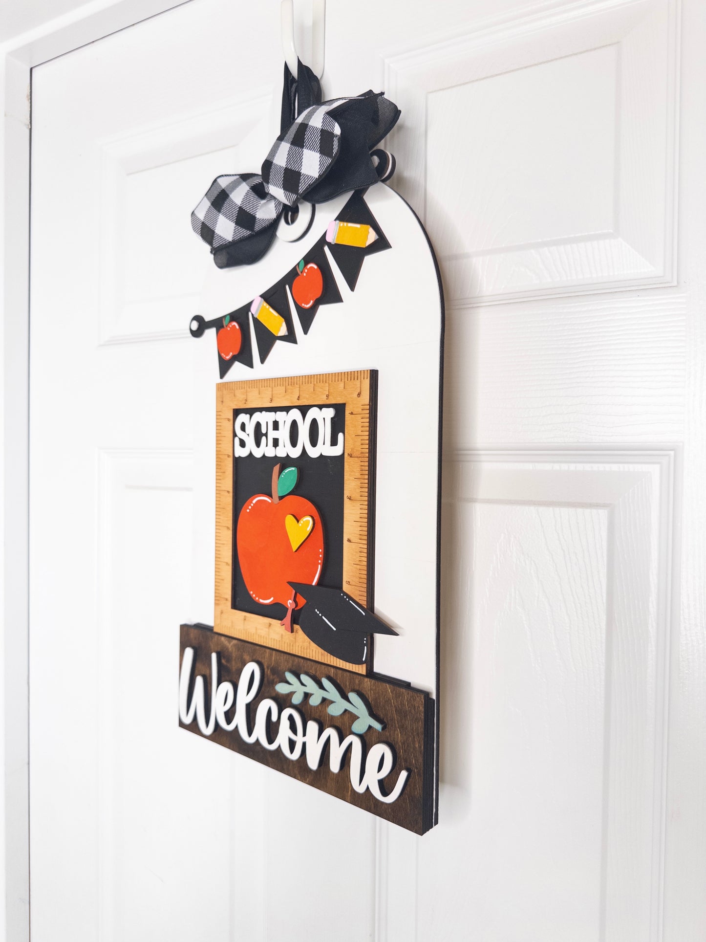 Decorative sign with 'School Welcome' text and apple illustration on a white door.