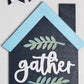 Decorative sign with 'gather' text and leaf designs on a blue and gray background