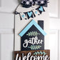 Decorative door hanger with 'gather' and 'Welcome' text on a white door.