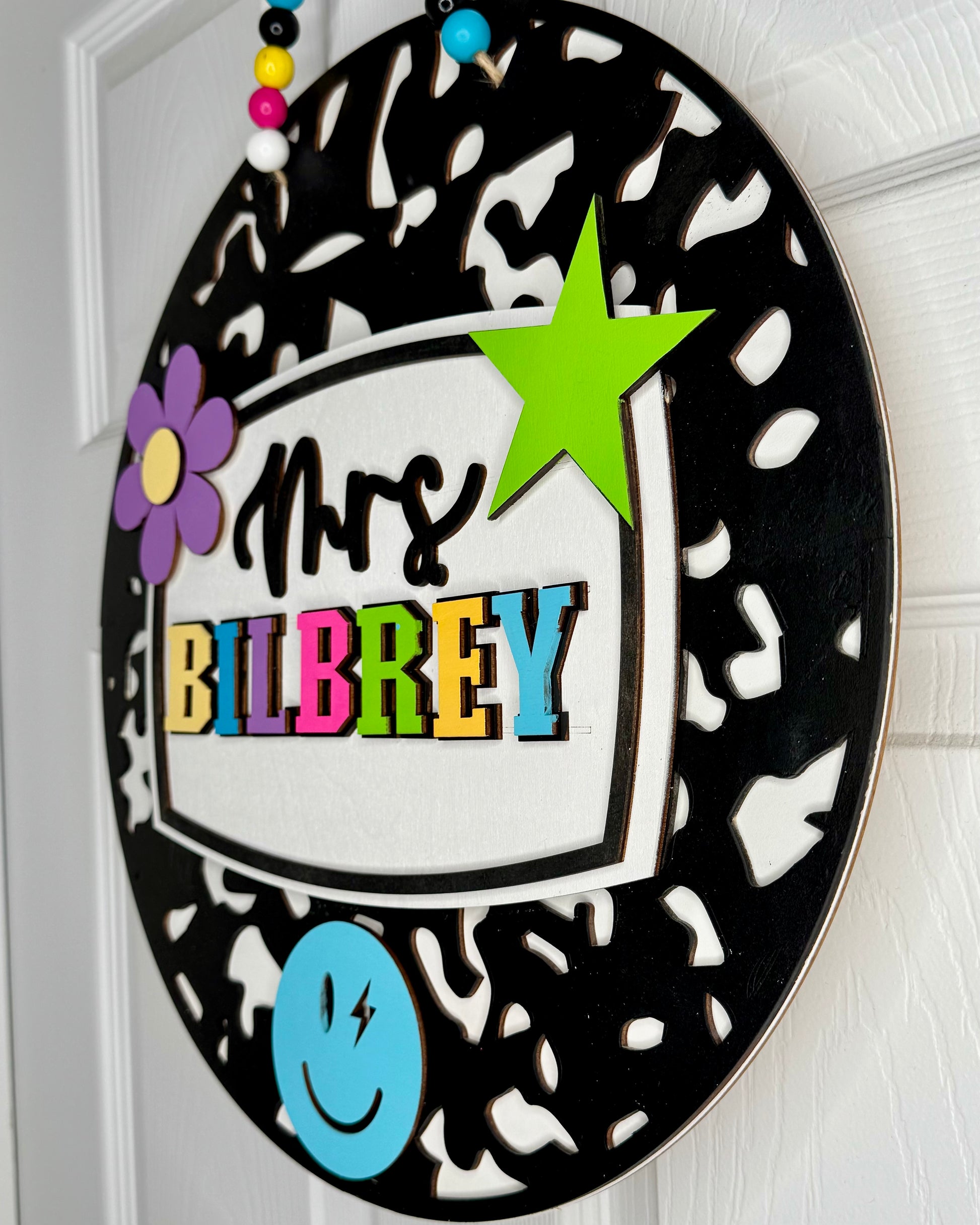 Decorative sign with colorful text and shapes on a black and white patterned background