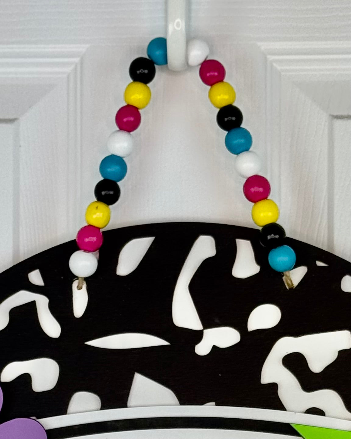 Colorful beaded necklace on a black and white patterned stand against a white background