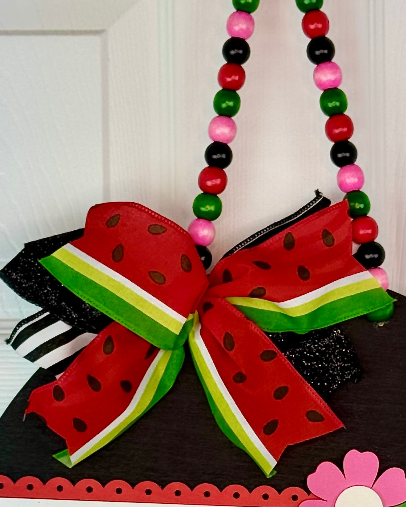 Decorative bow shaped like a watermelon with colorful beads on a white background