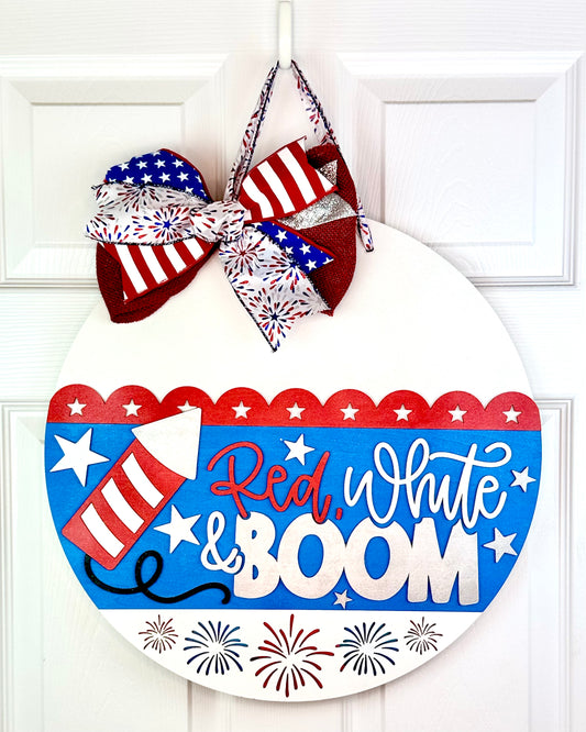 Decorative door hanger with 'Red, White & Boom' text and patriotic elements on a white background.